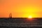 Windsurfer jumping on a wave facing the sunset