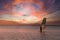 Windsurfer riding on a surfboard against a cloudy orange sunset. Empty copy space