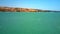 Windsurfer sails on blue ocean waves against coast