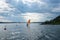 Windsurfing. Beautiful red orange sail. Windsurfer floats on surface of the water in gulf of the Baltic Sea. Dramatic sky with