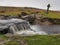 Windy Post granite cross behind a waterfall on the Grimsbridge and Sortridge leat, Dartmoor National Park, Devon