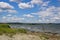 Windy summer day - waves on a lake under a blue sky with cumulus clouds. A pair of seagulls flies over the coast.