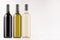 Wine bottles collection different colors - transparent, green, black- on white wooden board, mock up, copy space.