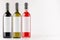 Wine bottles collection - red, green, black- with blank white labels on white wooden board, mock up, copy space.