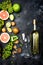 Wine concept. Bottle and glass of young white bio wine with green grapes, grapefruit and other fruit on a gray stone background