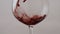 Wine glass filled rose alcohol drink in super slow motion close up. Red beverage