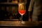 Wine glass with fizzy drink decorated with gold stands on bar counter