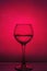 Wine glass with liquid on a red background.