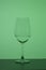 Wine glass on a long stem. A little drink is poured into it. In back green