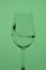 Wine glass on a long stem. A little drink is poured into it, a splash is visible. In back green