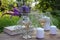 Wine glasses decorated with flowers, book, bouquet of lavender, veronica flowers in vase, candles on a wooden table
