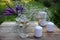 Wine glasses decorated with flowers, bouquet of lavender, veronica flowers in vase, candles on a wooden table in the summer garden