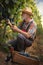 Wine grower with a straw hat squat among vines