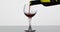 Wine. Red wine pouring in broken wine glass on the wet surface