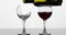 Wine. Red wine pouring into normal and broken wine glasses on the wet surface