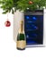 Wine refrigerator and bottle of champagne under Christmas tree.