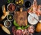 Wine snack set with empty wooden board in center. Glass of red, meat selection, mediterranean olives, sun-dried tomatoes