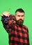 Winegrower with strict face holds cluster of grapes.