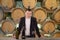 Winemaker inspecting quality of red wine, standing near bottles racks in winery vault