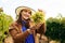 winemaker smilling adult woman with hat holding a bunch of white grape