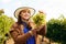 winemaker smilling adult woman with hat holding a bunch of white grape