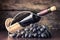 Winery background. Bottle of red wine with cluster of dark blue grapes on wooden table