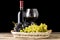 Winery still-life. Varieties of grapes with wineglass and bottle of wine on black background