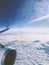 the wing of an airplane flying above clouds in the sun