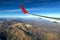 Wing of an airplane flying above the morning clouds and Andean mountain range