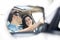 Wing mirror reflection of happy couple driving car