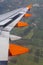 The wing of a plane with orange tail fins