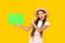 winking teen girl with copy space on green paper on yellow background. ok