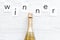 Winner congratulation concept with champagne on white wooden background top view