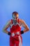 Winner emotions. Male boxer in red uniform and boxing gloves training isolated on blue background in neon. Strength