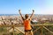 Winner fitness woman comes to the top of Barcelona and enjoying cityscape from belvedere. Excited attractive young woman in sports