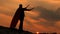 A winner with swords in his hand and in a red cloak stands on a mountain in the sunset light. free man plays a superhero