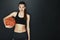 Winners never quit. Studio shot of a young woman holding a basketball against a dark background.