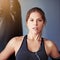 Winners train, losers complain. Cropped portrait of a female boxer standing in front of a punching bag.