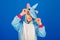 Winsome girl playfully posing in unicorn costume. Studio shot of emotional woman in kigurumi having fun on blue background