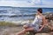 Winsome Relaxed Sensual Caucasian Brunette Female Girl in Casual Summer Beach Clothing Posing on Coastal or Sea Shoreline At Sunny