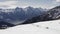 winter aerial view over group of people with snowshoes hiking down a snowy slope. In background magnificent snowy