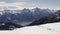 winter aerial view over group of people with snowshoes hiking down a snowy slope. In background magnificent snowy