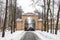 Winter alley and brick arch with cast iron gates in the park
