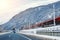 Winter alpine mountain highway and parallel railway road with intercity fast train and blue sky on background at bright cold sunny