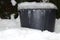 Winter atmospheric and motion picture with white snow, ice and mound of icicles on black container bucket, pail. Plastic