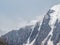 Winter atmospheric mountains landscape with blizzard in big snowy mountain top in low clouds. Awesome minimal scenery with white