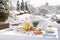 Winter Breakfast pancakes on the terrace outside the restaurant on the background of snow. Pancakes, fruit, juice, and