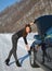 Winter car breakdown - young fashion woman trying to fix the car