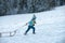 Winter children fun with sled. Winter outdoors games. Happy Christmas family vacation concept. Child sledging outside in