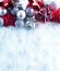 Winter and Christmas background. Beautiful sparkling silver and red Christmas decoration on a white snow background.